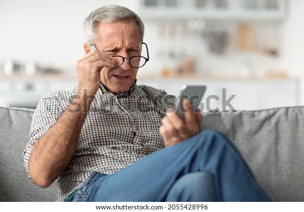 A man squinting at a smartphone, with a stock photo watermark overlaid on top of the image.